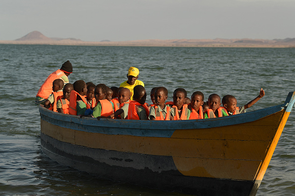 Les élèves de l'école primaire d'El-molo prennent un bateau pour se rendre à l'école après que le chemin a été submergé par la montée des eaux du lac Turkana, dans le nord du Kenya, le 13 juillet 2022. Photo de Simon MAINA / AFP via Getty Images.