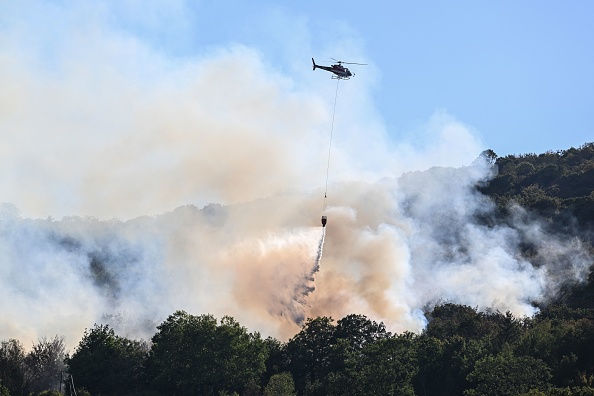 Un hélicoptère largue de l'eau sur des arbres lors d'un incendie de forêt dans le Jura. (Photo : JEAN-PHILIPPE KSIAZEK/AFP via Getty Images)