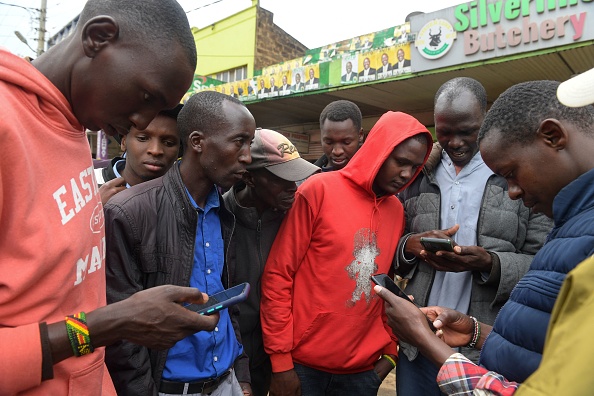 Les résidents regardent leurs téléphones en attendant les résultats de l'élection nationale du Kenya à Eldoret le 15 août 2022. Photo de SIMON MAINA/AFP via Getty Images.