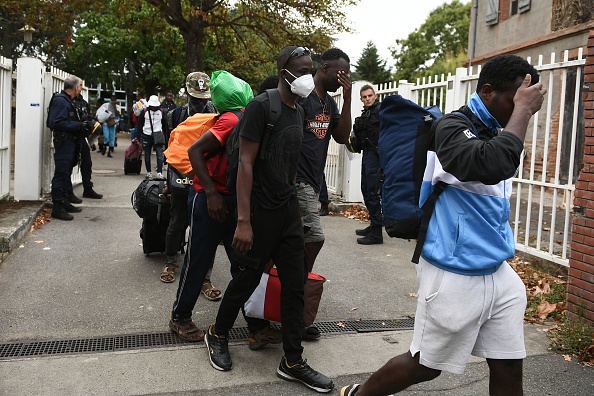 Des migrants quittent leur squat après avoir été évacués par les CRS. (Photo : VALENTINE CHAPUIS/AFP via Getty Images)
