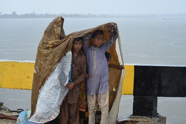 Des enfants déplacés avec leurs familles par les inondations dues aux fortes pluies de la mousson utilisent une bâche en plastique pour s'abriter, le 27 août 2022. Photo par ASIF HASSAN/AFP via Getty Images