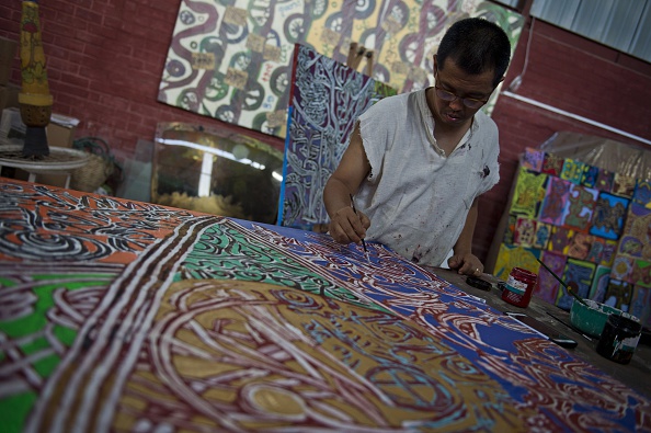 L’artiste birman Htein Lin, un ancien prisonnier politique travaille sur une peinture dans son atelier à Yangon. Photo ROMEO GACAD/AFP via Getty Images.