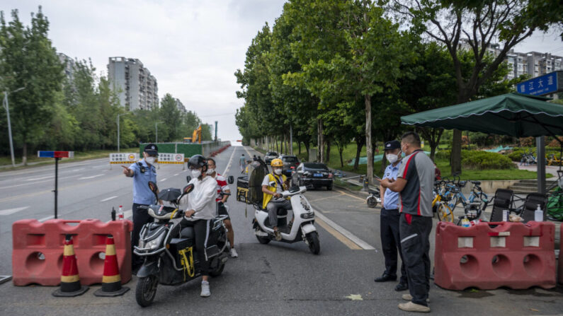 Des agents de police contrôlent l'identité des conducteurs de véhicules sur un barrage routier, le 1er septembre 2022, dans un contexte de mesures de restriction imposées par une vague d'épidémie de Covid-19 à Chengdu, dans la province du Sichuan (sud-ouest de la Chine). (CNS/AFP via Getty Images)