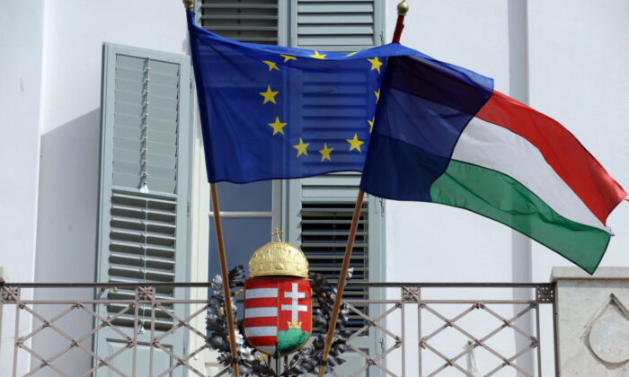 Les drapeaux de l'UE et de la Hongrie flottent devant un écusson hongrois au palais présidentiel de Budapest, capitale de la Hongrie, le 30 mars 2012. (Attila Kisbenedek/AFP via Getty Images)