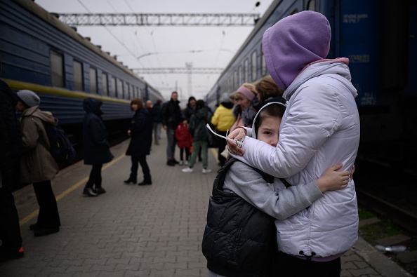 Une femme serre un enfant dans ses bras alors qu'un train se prépare à quitter la gare principale de Zaporijia, dans le sud de l'Ukraine, le 17 avril 2022. Photo par Ed JONES / AFP via Getty Images.
