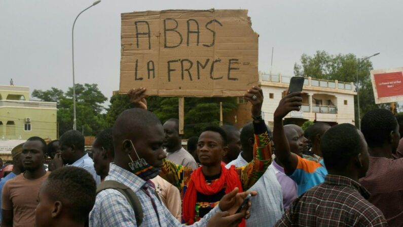 Un homme tient une pancarte sur laquelle on peut lire "À bas la France" alors que des personnes manifestent contre la présence militaire française au Niger, le 18 septembre 2022 à Niamey. (Photo by BOUREIMA HAMA/AFP via Getty Images)