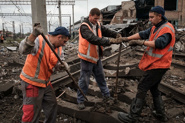 Des travailleurs retirent les boulons des voies ferrées bombardées à la gare de fret de Kharkiv, partiellement détruite par une frappe de missile russe le 28 septembre 2022. Photo de YASUYOSHI CHIBA/AFP via Getty Images.