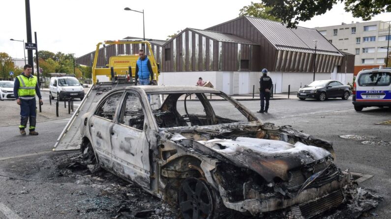 Des ouvriers retirent une voiture brûlée d'un parking après les violences de la nuit dans le quartier de Perseigne à Alencon, dans le nord-ouest de la France, le 28 septembre 2022. - Des policiers ont été visés par des feux d'artifice et une vingtaine de véhicules ont été brûlés dans la nuit du 27 septembre à Alencon, selon le parquet de la ville normande.  (JEAN-FRANCOIS MONIER/AFP via Getty Images)