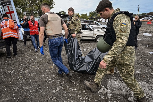 Les militaires ukrainiens portent un sac en plastique contenant le corps d'une des personnes tuées par une frappe de missile près de Zaporizhzhia le 30 septembre 2022. Photo Genya SAVILOV/AFP via Getty Images.