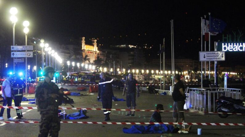 Des soldats, des policiers et des pompiers marchent près des cadavres recouverts d'un drap bleu sur le front de mer de la Promenade des Anglais, dans la ville de Nice, le 15 juillet 2016, après qu'un camion a foncé dans une foule assistant à un feu d'artifice. (Photo : VALERY HACHE/AFP via Getty Images)