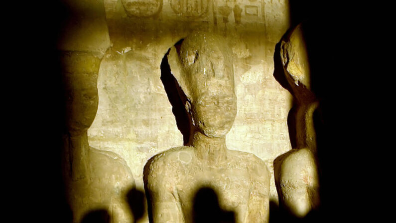 Illustration - Une photo prise en 2002 montre des touristes projetant leurs ombres alors qu'un rayon de lumière illumine la statue de Ramsès II à l'intérieur du temple d'Abou Simbel, au sud d'Assouan, en Haute-Égypte. (Photo credit should read KHALED DESOUKI/AFP via Getty Images)