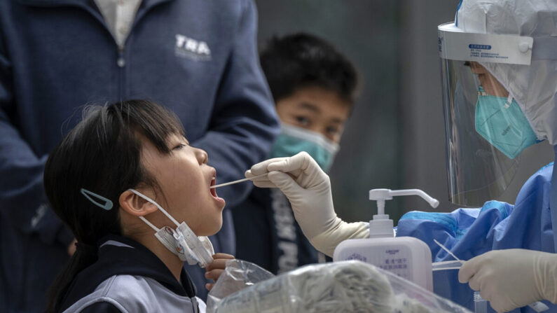 Une jeune fille est soumise à un test d'acide nucléique effectué par un professionnel de la santé dans un site de dépistage improvisé Covid-19 à Pékin, le 29 avril 2022. (Kevin Frayer/Getty Images)