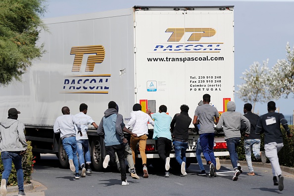 Des migrants tentent d'ouvrir la porte arrière d'un camion au port ferry de Bretagne à Ouistreham, le 18 septembre 2018.  (CHARLY TRIBALLEAU/AFP via Getty Images)