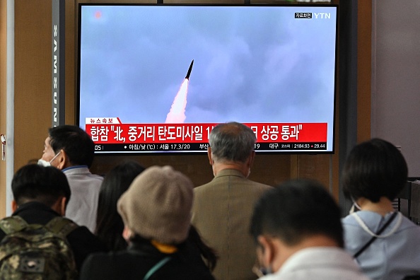 Des passants regardent un écran alors que la Corée du Nord a tiré ce mardi un missile balistique de moyenne portée. Gare de Séoul, le 4 octobre 2022. (Photo by JUNG YEON-JE/AFP via Getty Images)