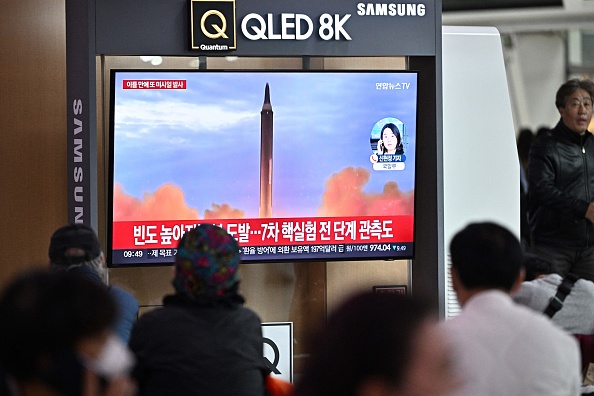 Des personnes sont assises près d'une télévision diffusant un journal télévisé avec des images d'archives d'un essai de missile nord-coréen, dans une gare ferroviaire de Séoul, le 6 octobre 2022.  (Photo : ANTHONY WALLACE/AFP via Getty Images)