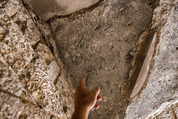 Un archéologue israélien montre le nom de Bubenberg gravé dans la pierre du tombeau du roi David, sur le mont Sion, près de Jérusalem. (Photo :  MENAHEM KAHANA/AFP via Getty Images)