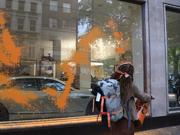 Un manifestant écologiste  de Just Stop Oil pulvérise une substance orange sur le magasin Jack Barclay Bentley à Berkeley Square, le 26 octobre 2022 à Londres en Angleterre. (Photo : Isabel Infantes/Getty Images)