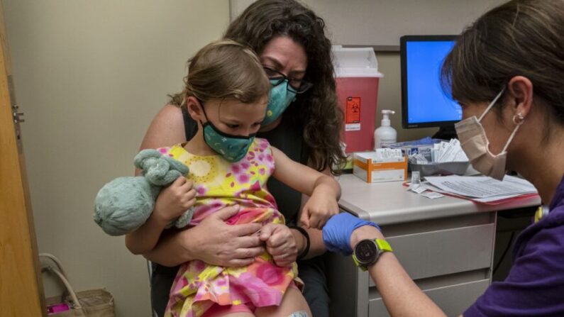 Nora Burlingame, 3 ans, est assise sur les genoux de sa mère, Dina Burlingame, et reçoit un encouragement de l'infirmière Luann Majeed après avoir reçu sa première dose du vaccin Pfizer Covid-19 au UW Medical Center-Roosevelt à Seattle, Wash. le 21 juin 2022. (David Ryder/Getty Images)