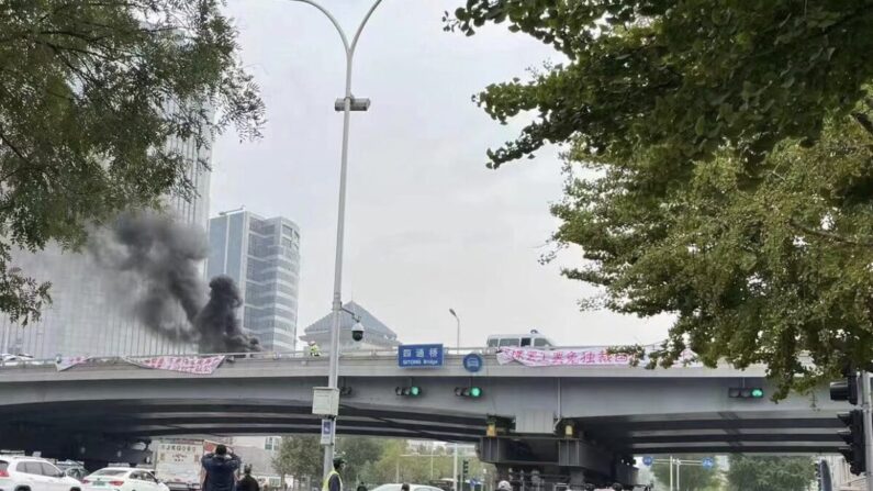 Les passants photographient les banderoles de protestation politique sur un viaduc à Pékin, le 13 octobre 2022. (Capture d'écran du compte Twitter Fangshimin via Epoch Times)
