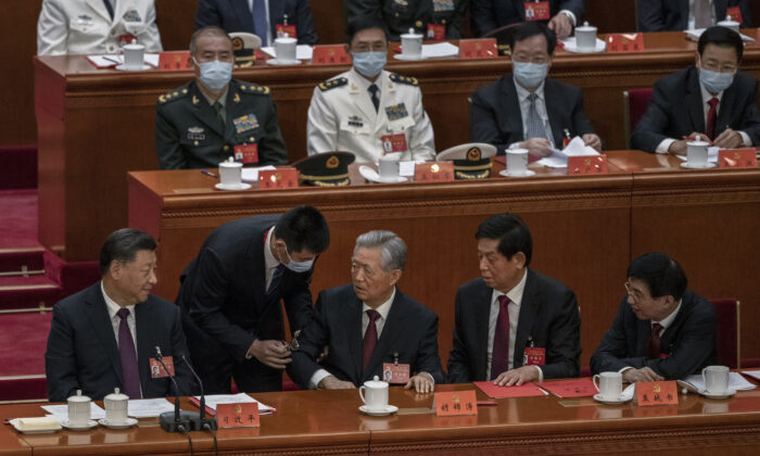 Le dirigeant chinois Xi Jinping (premier rang à g.), Li Zhanshu et Wang Huning (à dr.), regardent l'ancien dirigeant Hu Jintao (au c.) parler à Xi Jinping alors qu'on l'aide à quitter prématurément la session de clôture du 20e Congrès du Parti communiste chinois au Grand palais du Peuple à Pékin, le 22 octobre 2022. (Kevin Frayer/Getty Images)