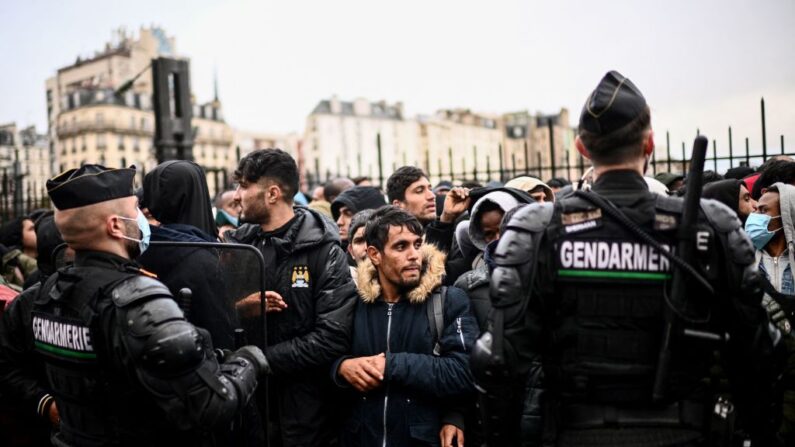 Encadrés par l'unité mobile anti-émeute des gendarmes, des migrants attendent pour embarquer dans des bus afin de trouver un abri temporaire, le 17 novembre 2022.(Photo: CHRISTOPHE ARCHAMBAULT/AFP via Getty Images)