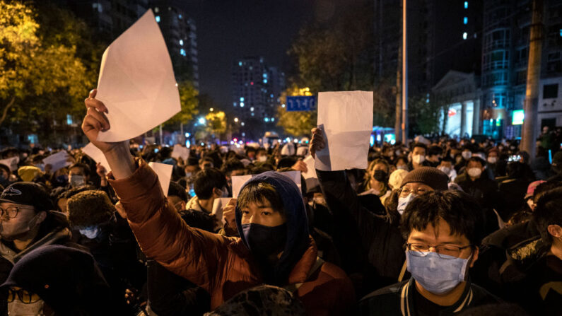 Des manifestants brandissent des morceaux de papier contre la censure et la politique "zéro Covid" en Chine, le 27 novembre 2022, à Pékin. (Photo: Kevin Frayer/Getty Images)