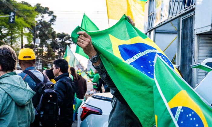 Un manifestant brésilien tient un drapeau à Curitiba le 4 novembre 2022. Le pays, première économie d'Amérique latine, voit de nombreuses personnes descendre dans la rue, après des élections qui suscitent la controverse. (Frederico Vidovix/Epoch Times)