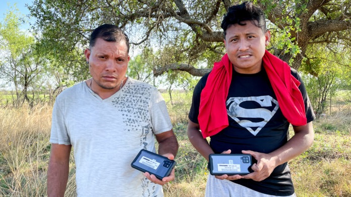 Deux ressortissants nicaraguayens avec les téléphones portables reçus de la part de la patrouille frontalière, dans le comté de Kinney, au Texas, le 29 avril 2022. (Charlotte Cuthbertson/Epoch Times)