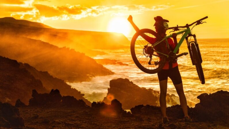 Succès, réussite, accomplissement et victoire d'une cycliste  en VTT, célébrant son arrivée au sommet.(Shutterstock)