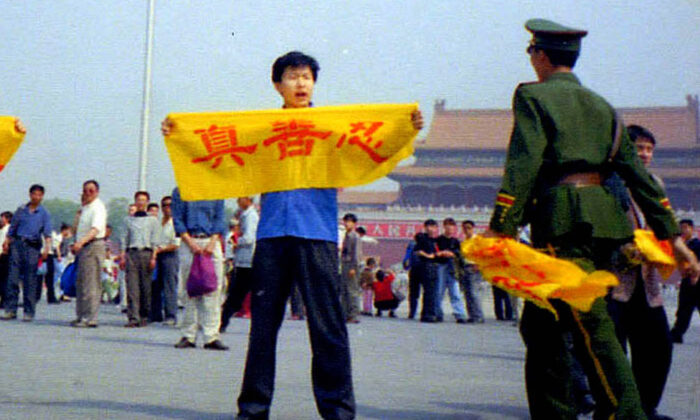 Pratiquant de Falun Gong sur la place Tiananmen, à Pékin, en passe d’être arrêté alors qu'il tient une bannière portant les caractères chinois de "vérité », « compassion », « tolérance", les principes fondamentaux du Falun Gong. (Avec l'aimable autorisation de Minghui.org)