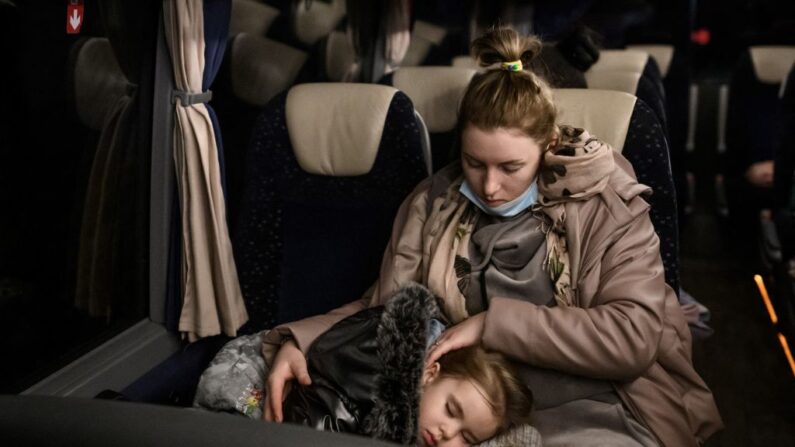 Une réfugiée ukrainienne tient son enfant endormi dans un bus après avoir atterri à l'aéroport de Zurich, le 22 mars 2022. (Photo: FABRICE COFFRINI/AFP via Getty Images)