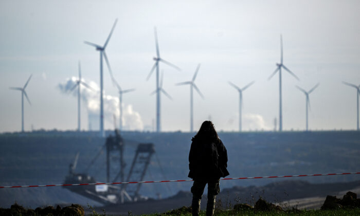 Une femme se tient devant la mine de lignite à ciel ouvert avec des éoliennes en arrière-plan, près de Lützerath, dans l’ouest de l’Allemagne, le 12 novembre 2022. (Ina Fassbender/AFP via Getty Images)