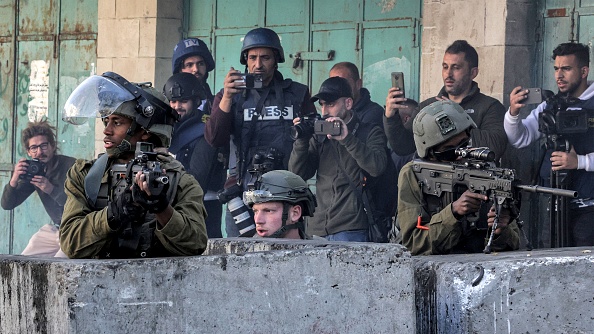 Des soldats israéliens, flanqués de journalistes, s'abritent derrière des barrières en béton le 20 décembre 2022. (Photo HAZEM BADER/AFP via Getty Images)