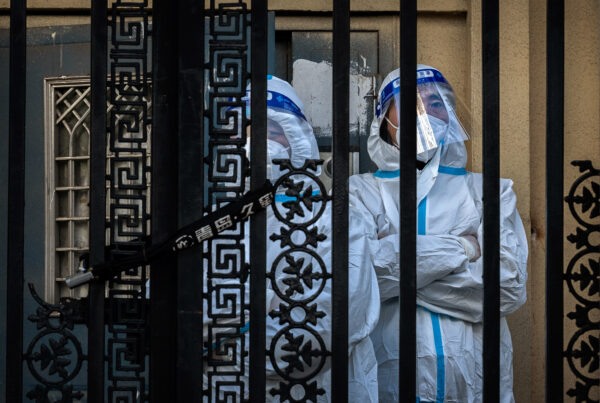 Agents de contrôle des épidémies derrière le portail verrouillé d'un immeuble résidentiel du quartier central des affaires à Pékin, le 26 novembre 2022. (Kevin Frayer/Getty Images)