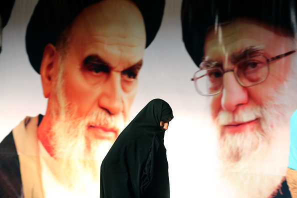 Une femme iranienne passe devant une affiche géante du leader suprême, l'Ayatollah Ali Khamenei et du fondateur de la République islamique Ayatollah Ruhollah Khomeini d'Iran.  (Photo : ATTA KENARE/AFP via Getty Images)