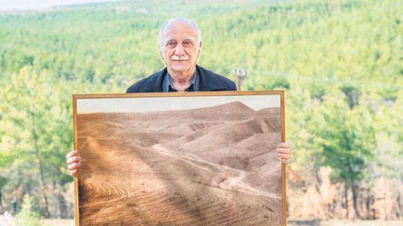 Hikmet Kaya arbore la photo de l’ancienne colline devenue la forêt dense que l’on voit derrière lui (photo Facebook : association Yardimeli)