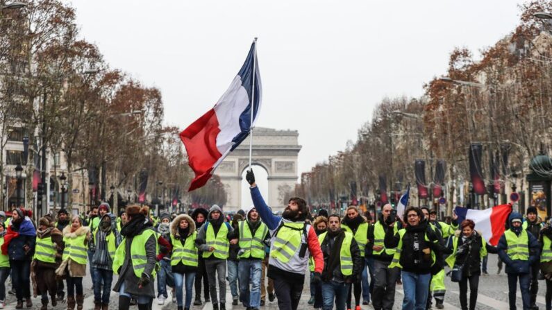 Un gilet jaune brandit le drapeau français lors d'une manifestation sur les Champs-Élysées, le 15 décembre 2018. (Photo: VALERY HACHE/AFP via Getty Images)