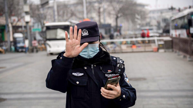 Un officier de police fait signe à un journaliste de ne pas photographier à Pékin, en Chine, le 5 mars 2021. (Nicolas Asfouri/AFP via Getty Images)