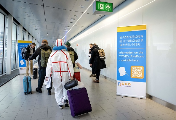 Des voyageurs arrivant de Chine passent devant des bannières d'information et reçoivent des kits d'autotest Covid-19 gratuits, à l'aéroport Schiphol d'Amsterdam, le 4 janvier 2023. (Photo : ROBIN VAN LONKHUIJSEN/ANP/AFP via Getty Images)