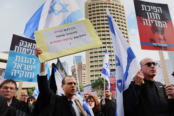 Un homme tient une pancarte sur laquelle est écrit en hébreu "nous ne vous laisserons pas revenir à l'époque du Mandat britannique" lors d'une manifestation d'avocats contre les plans controversés du gouvernement israélien visant à remanier le système judiciaire, devant la Cour de justice du district de Tel Aviv, le 12 janvier 2023. (Photo: JACK GUEZ/AFP via Getty Images)