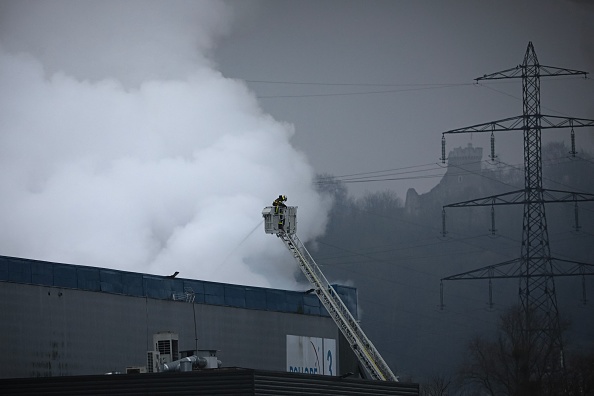 Des pompiers pulvérisent de l'eau après avoir combattu un incendie survenu dans la nuit dans un bâtiment industriel appartenant à Bolloré Logistics, à Grand-Couronne, au sud de Rouen, le 17 janvier 2023. (Photo : LOU BENOIST/AFP via Getty Images)