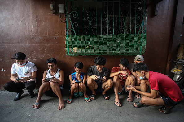 des personnes jouent à Axie Infinity, un jeu NFT où les joueurs gagnent des jetons qui peuvent être échangés contre des crypto-monnaies ou de l'argent à Manille. (JAM STA ROSA/AFP via Getty Images)