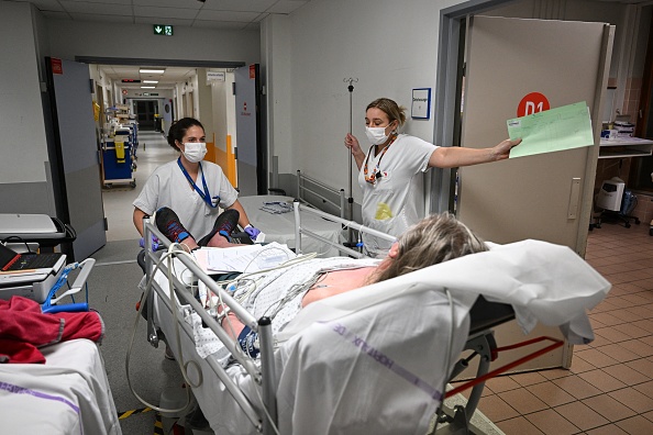 Une infirmière pousse un patient sur un lit au service des urgence. (Photo : SÉBASTIEN BOZON/AFP via Getty Images)