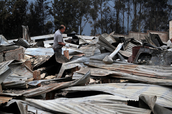 Un homme déambule au milieu de maisons détruites par un incendie de forêt dans les collines de Tome, au Chili. (Photo : JAVIER TORRES/AFP via Getty Images)