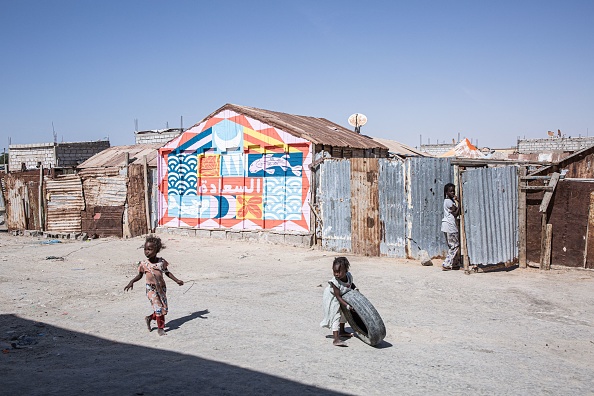 Des enfants jouent devant une peinture murale réalisée par l'artiste Seb Toussaint à Nouakchott le 1er janvier 2023, dans le cadre de son projet d'art de rue "Share the World". (Photo : MED LEMIN RAJEL/AFP via Getty Images)