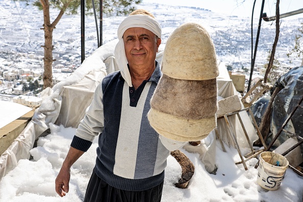 Le chapelier Youssef Akiki pose avec l'un de ses chapeaux de laine libanais finis, appelés "Labbadeh", dans son atelier du village de montagne de Hrajel, Liban. (JOSEPH EID/AFP via Getty Images)