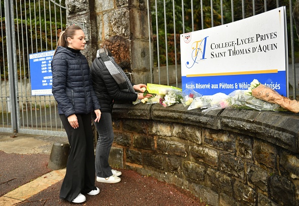Des élèves déposent des fleurs devant le portail d'entrée du collège Saint-Thomas d'Aquin à Saint-Jean-de-Luz. (GAIZKA IROZ/AFP via Getty Images)