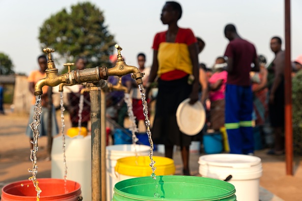 Des personnes font la queue pour récupérer des seaux d'eau dans un puits foré par des ONG dans le canton de Glen View, au Zimbabwé. (JEKESAI NJIKIZANA/AFP via Getty Images)