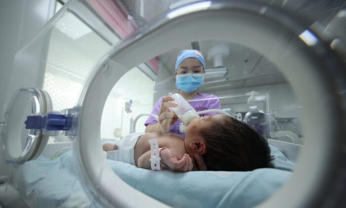Un membre du personnel médical nourrit un bébé dans un hôpital de Danzhai, dans la province chinoise du Guizhou (sud-ouest), le 11 mai 2021. (STR/AFP via Getty Images)