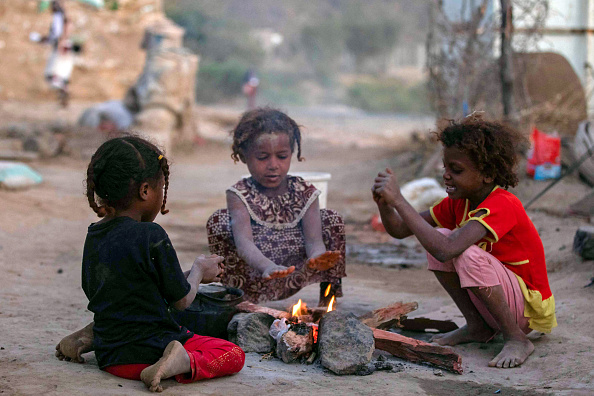 Des enfants se réchauffent près d'un feu dans un camp de déplacés à la périphérie de la troisième ville du Yémen, Taez. (AHMAD AL-BASHA/AFP via Getty Images)